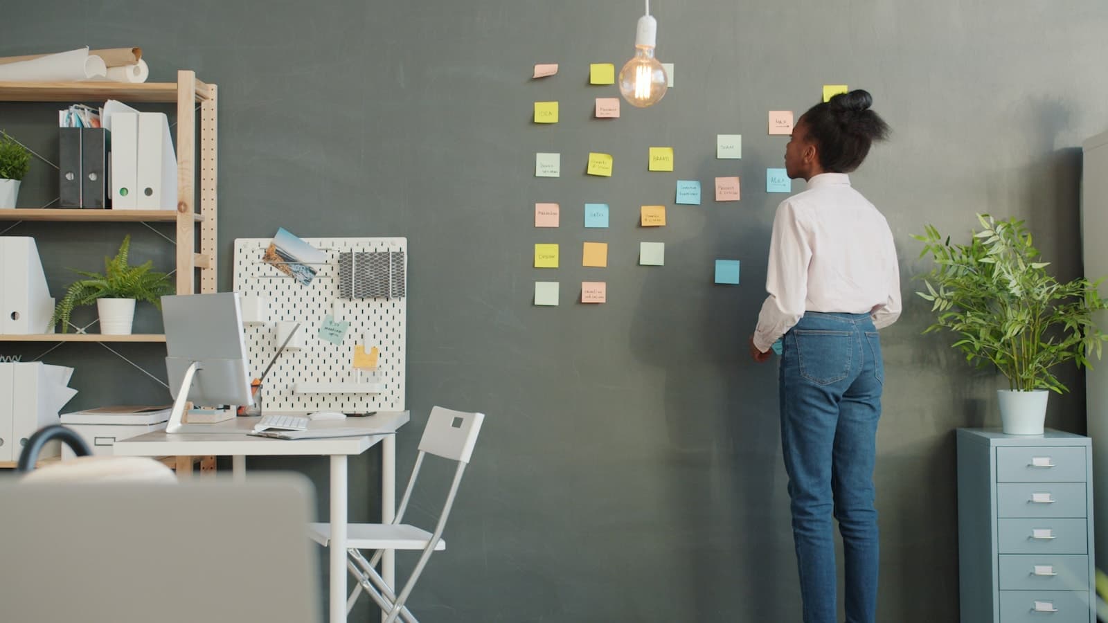 African founder facing a colourful wall of sticky notes, stuck between too many ideas